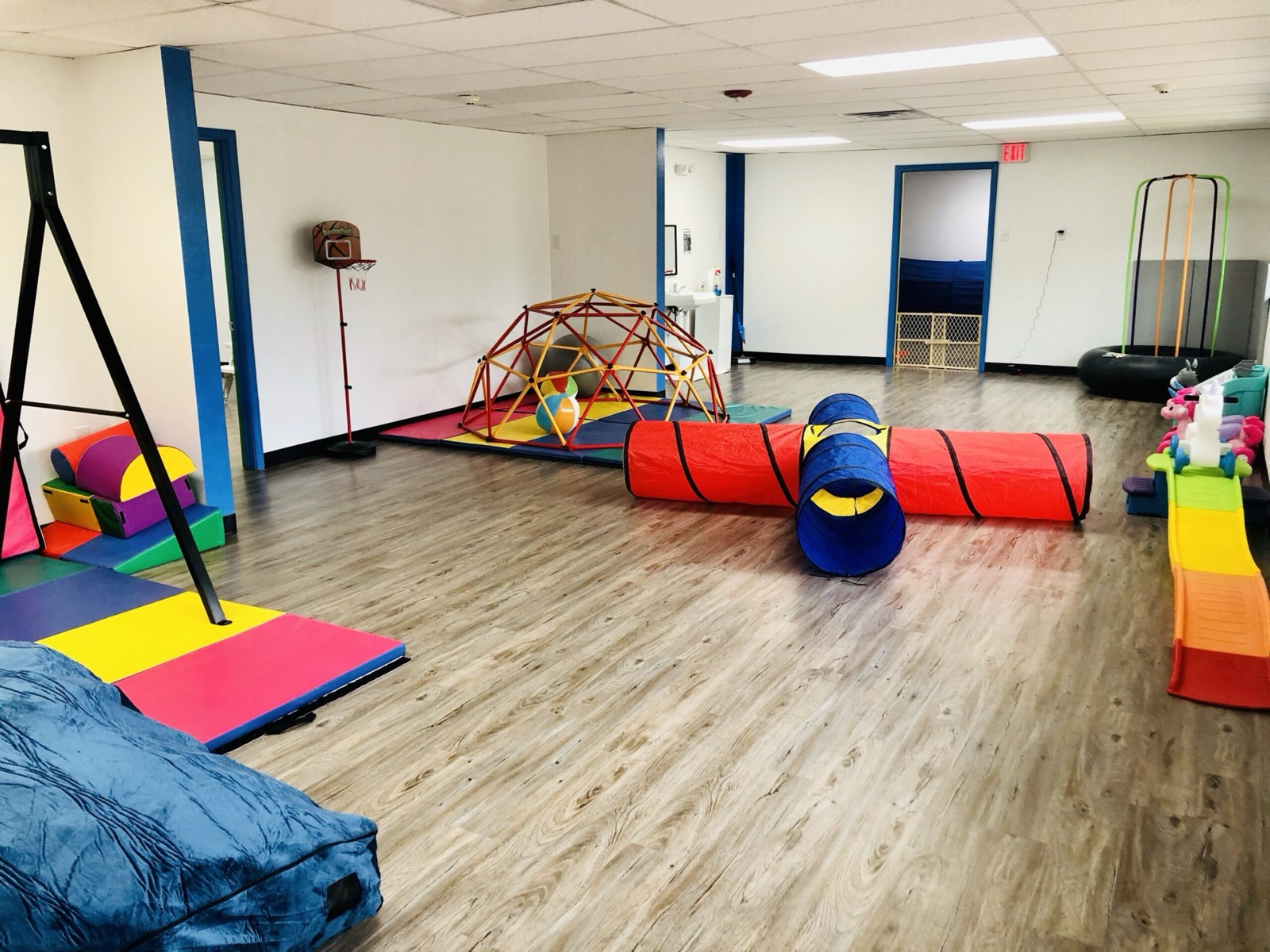 Gross-motor therapy gym with a rainbow crawl tunnel and soft play equipment